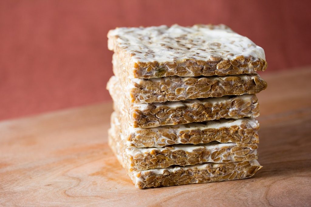 Tempeh is a soy-based food that is similar to tofu but involves the fermentation of the soybeans.